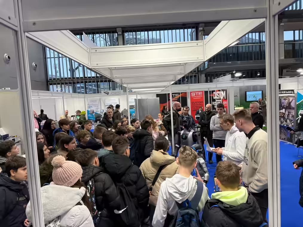 Skupina šolarjev pred robotom na sejemskem prostoru HIPROJECT