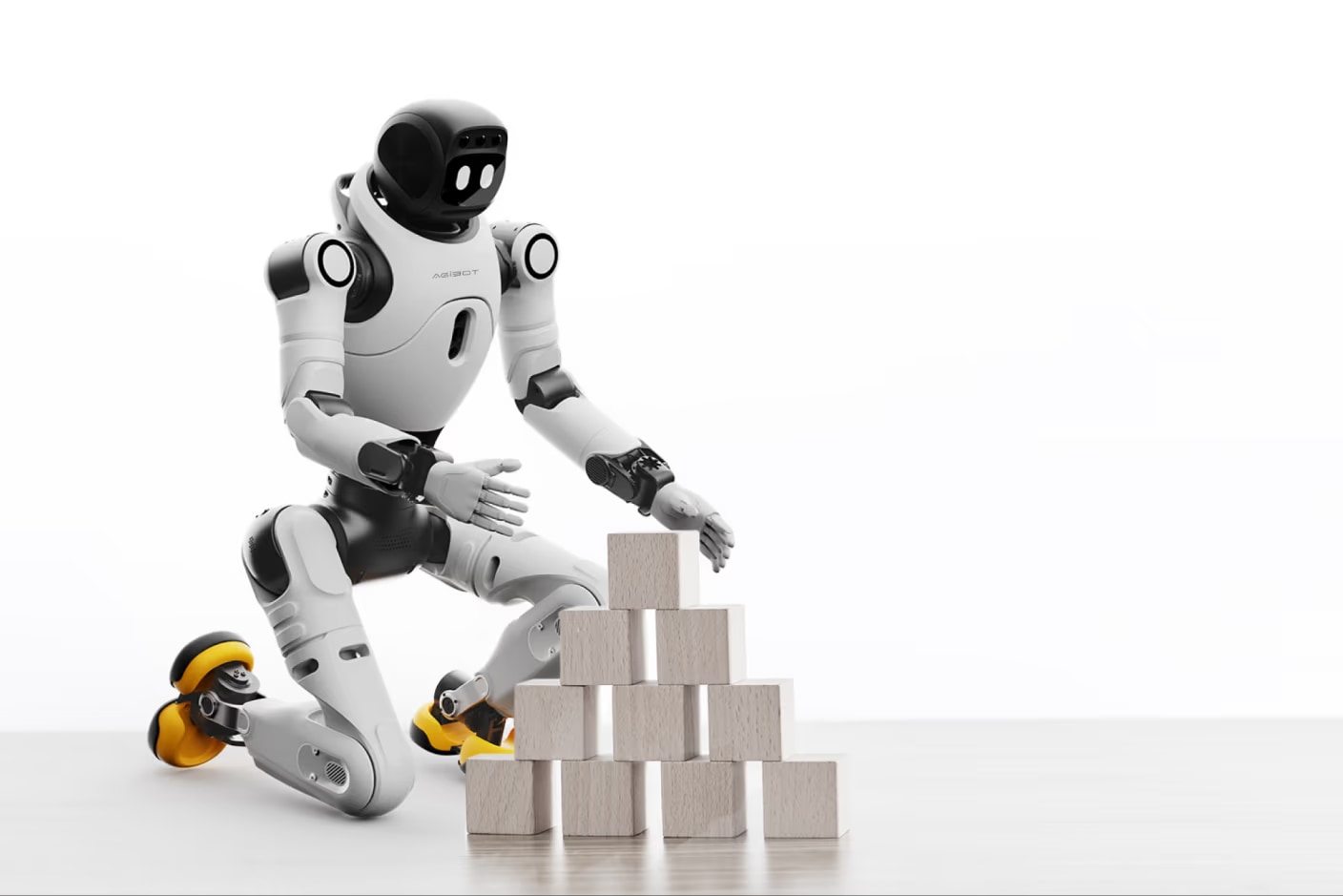 Robot X2 Ultra kleči ob mizi in zlaga lesene kocke v piramido