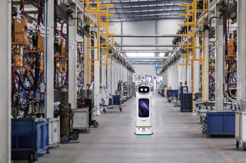 Робот CADEBOT у производној хали између високих полица