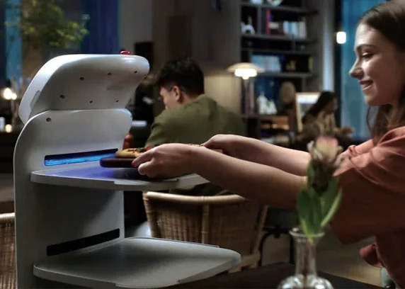 Гост узима тањир са таце робота CADEBOT за столом у ресторану