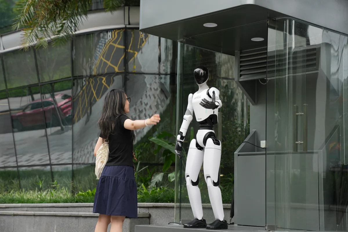 Eine Besucherin trifft den Roboter Walker C1 vor einem Glaseingang